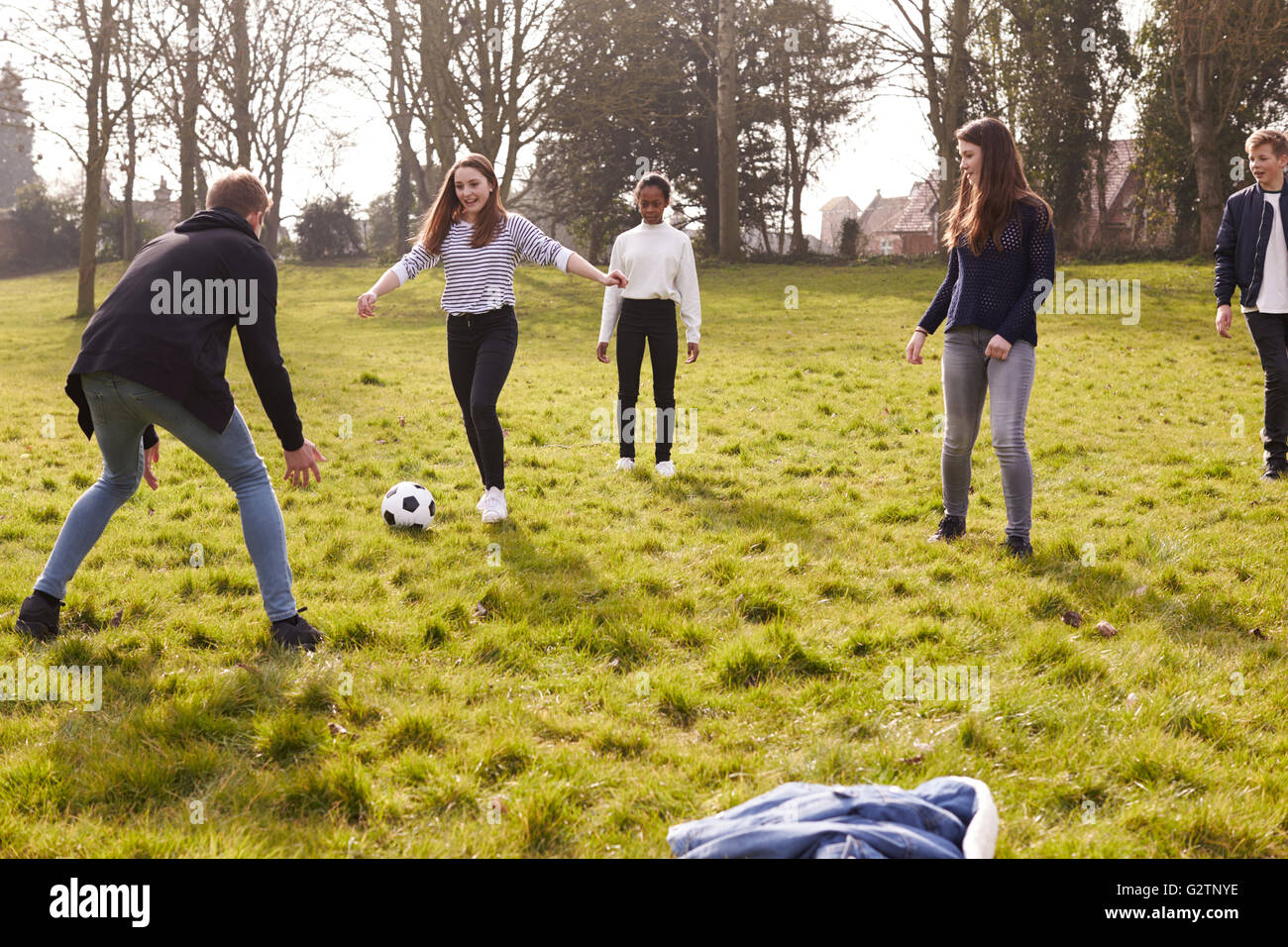 Gruppe von Jugendlichen spielen Fußball im Park zusammen Stockfoto
