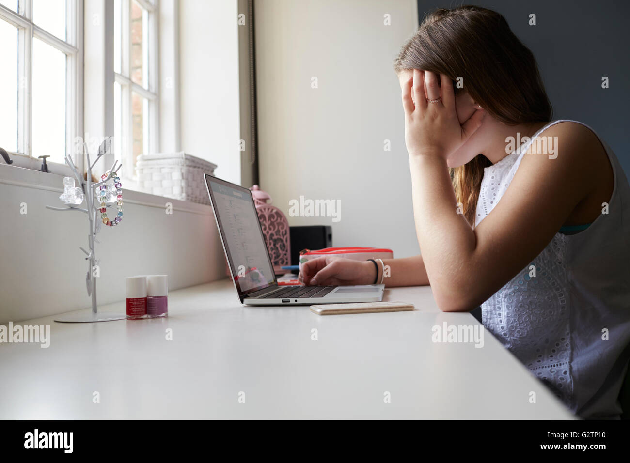 Unglückliche Teenager Opfer von Online-Mobbing im Schlafzimmer Stockfoto