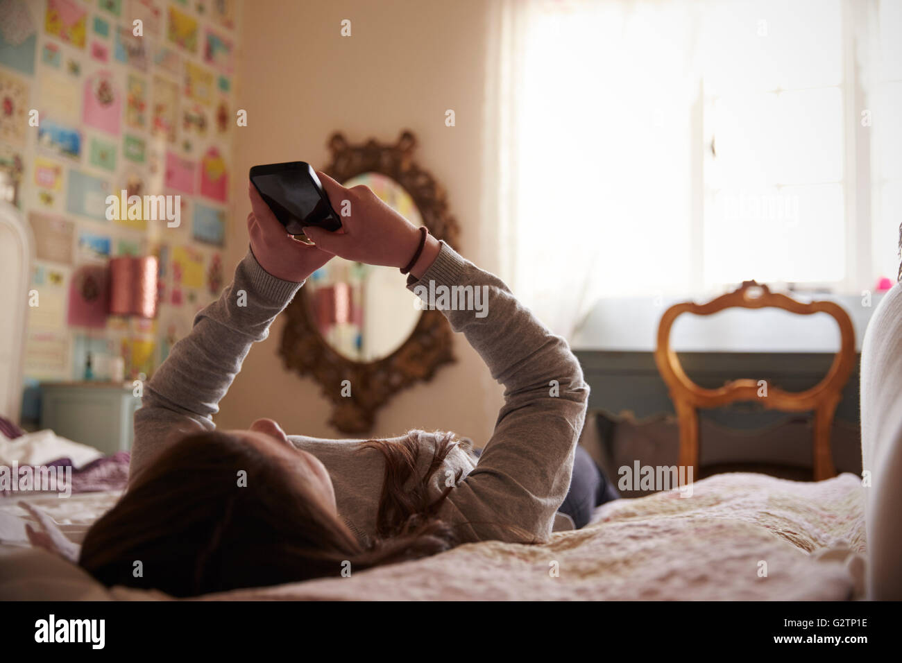 Teenager-Mädchen mit Handy im Schlafzimmer zu Hause Stockfoto