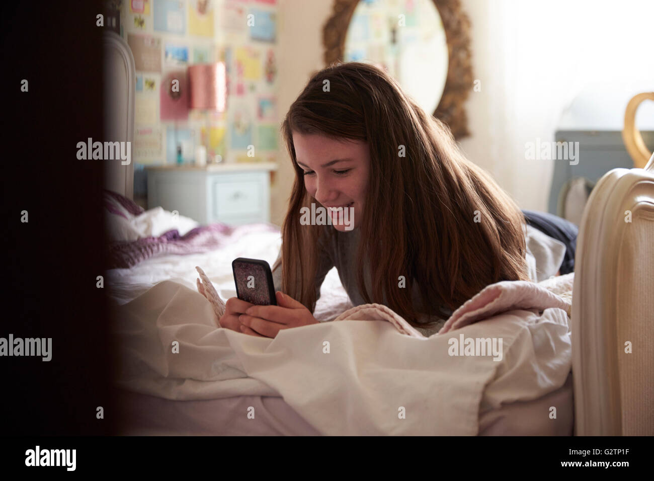 Teenager-Mädchen mit Handy im Schlafzimmer zu Hause Stockfoto