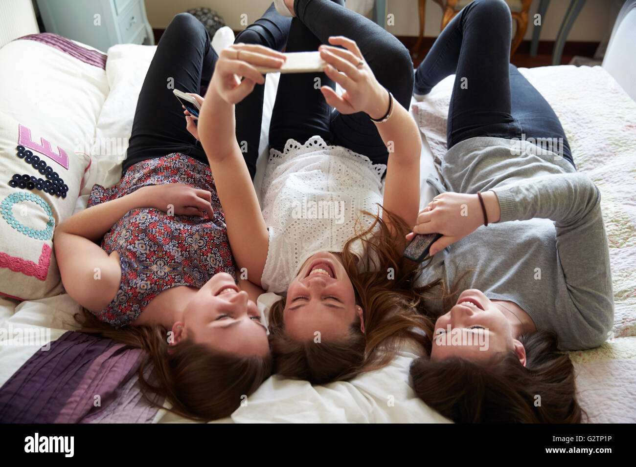 Drei Teenager, die Benutzung von Mobiltelefonen im Schlafzimmer zu Hause Stockfoto
