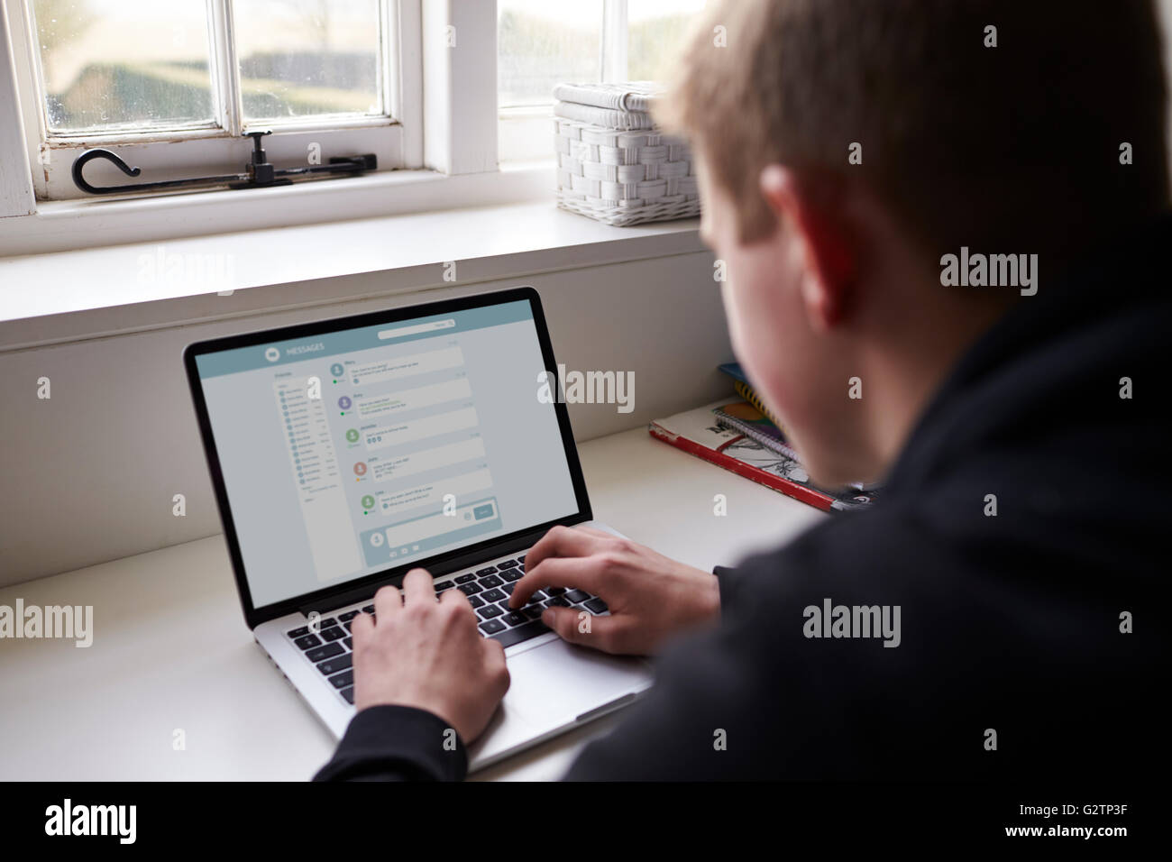 Teenager sitzen am Schreibtisch im Schlafzimmer mit Laptop Stockfoto