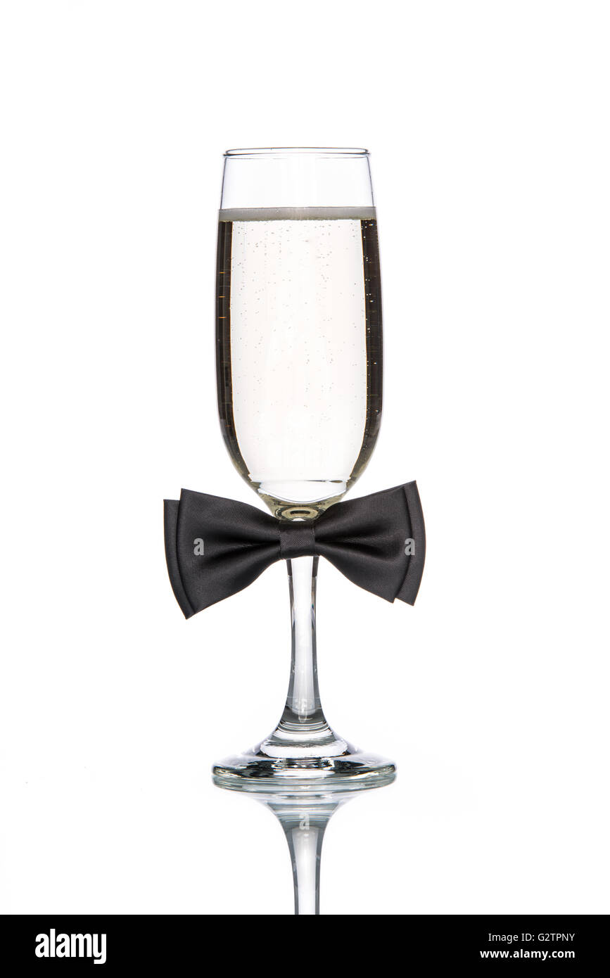 Glas Champagner mit schwarzer Fliege auf weißem Hintergrund Stockfoto