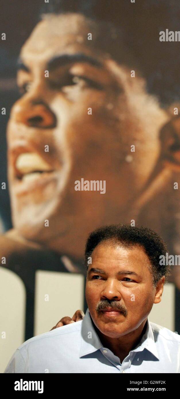 (Dpa) - Box-Legende Muhammad Ali darstellt, unter der ein Plakat mit Ali in früheren Zeiten, als er sein Buch das Buch präsentiert Messe in Frankfurt am Main, 9. Oktober 2003. Das Buch ist berechtigt "Ziege" (The Greatest Of All Times), kostet 7500 Euro und mehr als 30 kg wiegt. Die Boxer, der Parkinsonschen Krankheit geprägt ist, während der Präsentation kein einziges Wort sprechen, aber im Hintergrund posierte für Fotografen und Kameraleute. | weltweite Nutzung Stockfoto