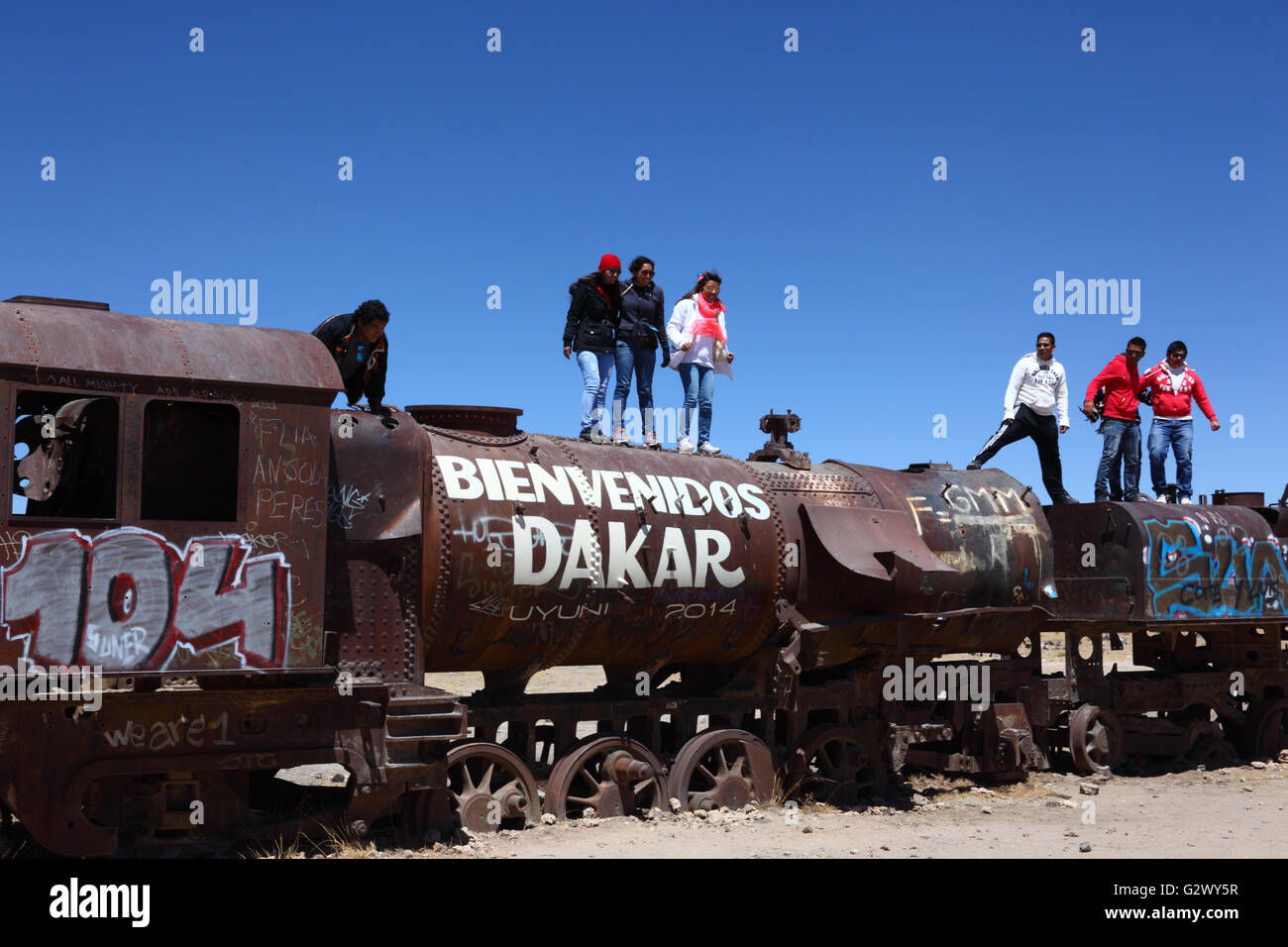 Studenten stand am Anfang von alten Dampfmaschine mit willkommen Dakar Graffiti gemalt, Uyuni Zug Friedhof, Bolivien Stockfoto