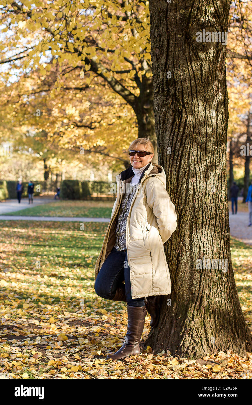 Reif, lächelnde Frau im Herbst Park am Baum, vertikale Stockfoto