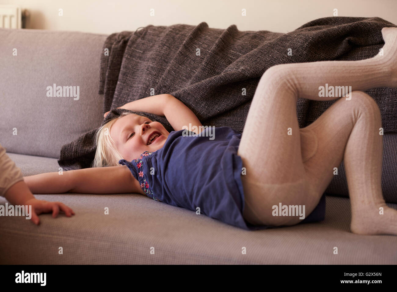 Junges Mädchen auf dem Sofa liegend und lachen Stockfoto