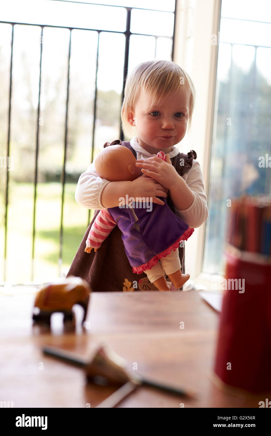 Junges Mädchen mit Puppe spielt zu Hause Stockfoto