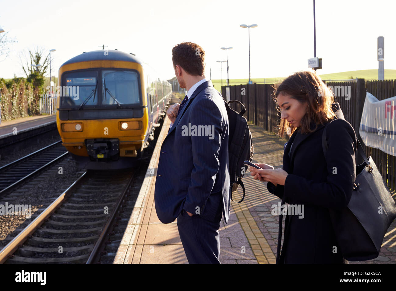 Pendler am Bahnsteig, die Benutzung von Mobiltelefonen Stockfoto