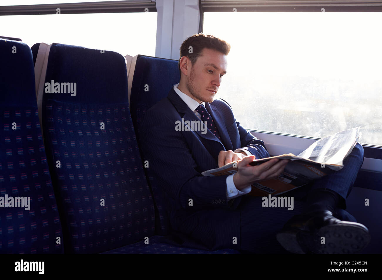 Geschäftsmann pendeln zur Arbeit, Zeitunglesen auf Zug Stockfoto