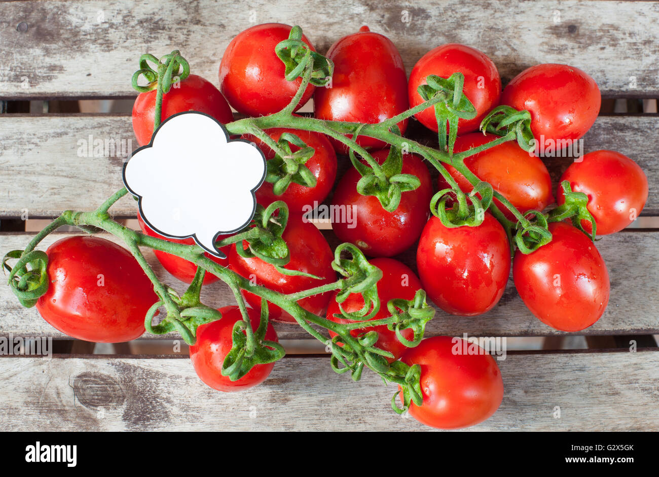 Zweig der rote Reife Kirschtomaten mit weißen Comic-Stil-Label auf Holztisch Stockfoto