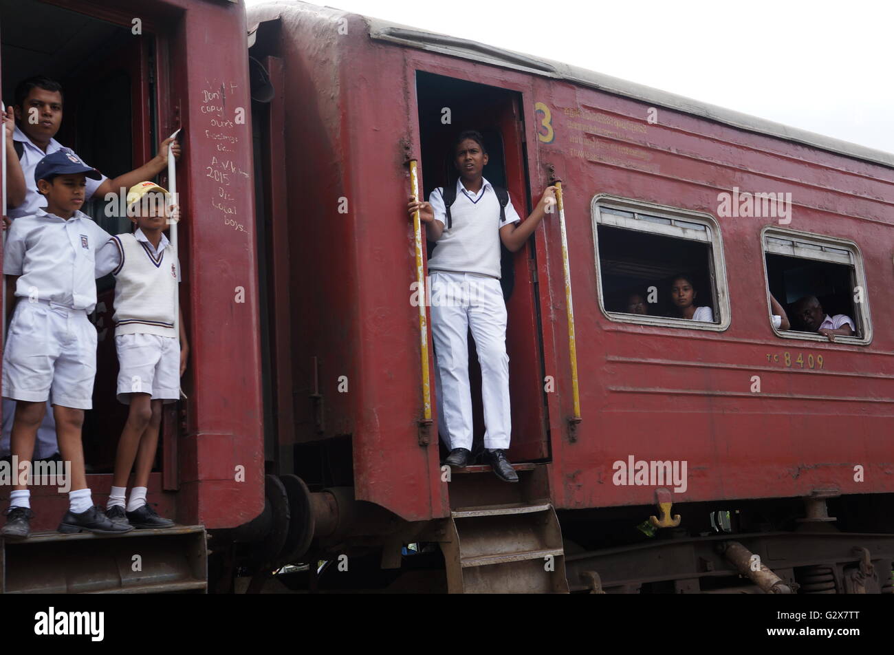 Junge Studenten in Uniform auf dem Weg zurück vom Schule stehen auf den Plattformen von einem alten Zug, Kandy, Sri Lanka. Stockfoto