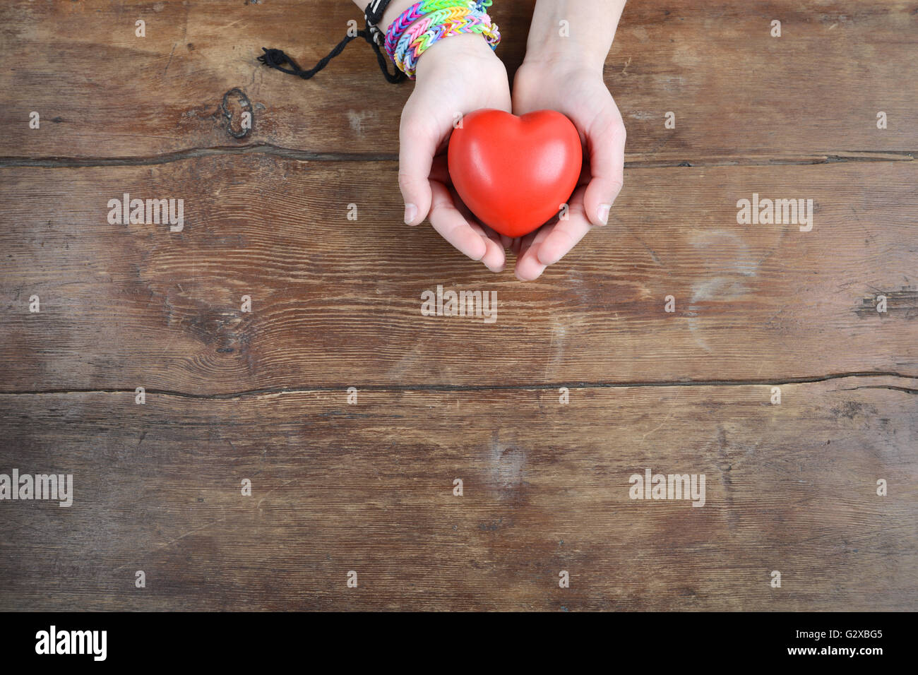 rotes Herz in Händen über Vintage Holz-Hintergrund Stockfoto