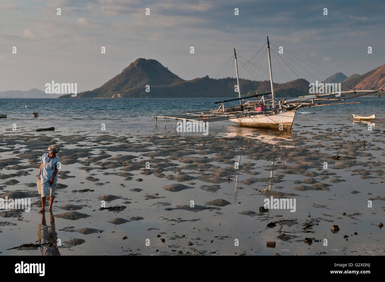 Komodo Insel, Fischerdorf, Mann mit Fisch vom Boot in Richtung des Dorfes bei Ebbe Stockfoto