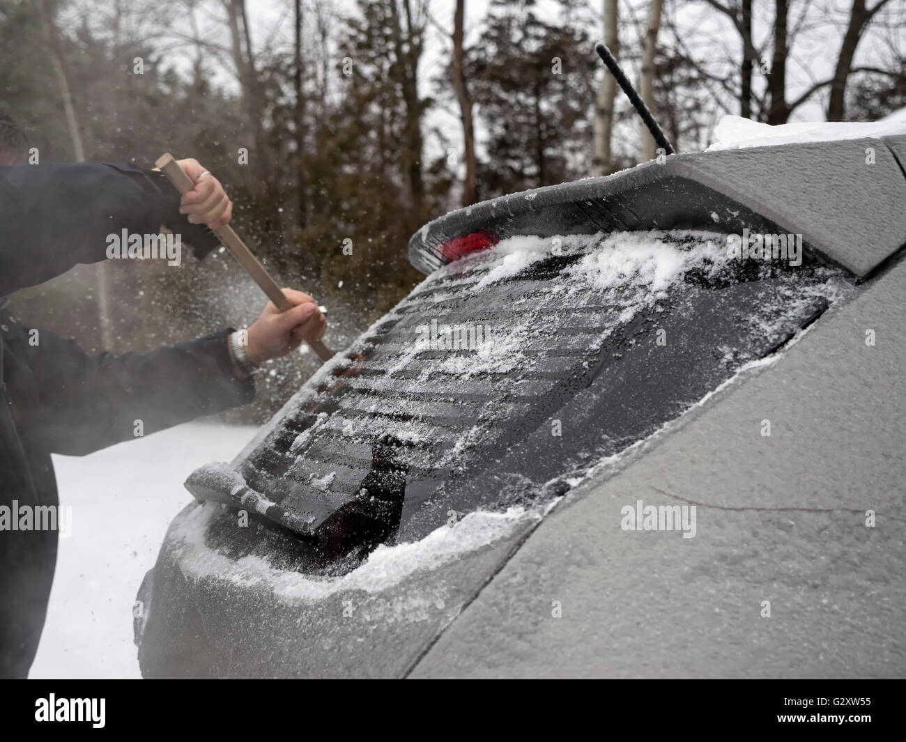 Schaben Eis aus der hinteren Windsheld eines Autos im winter Stockfoto