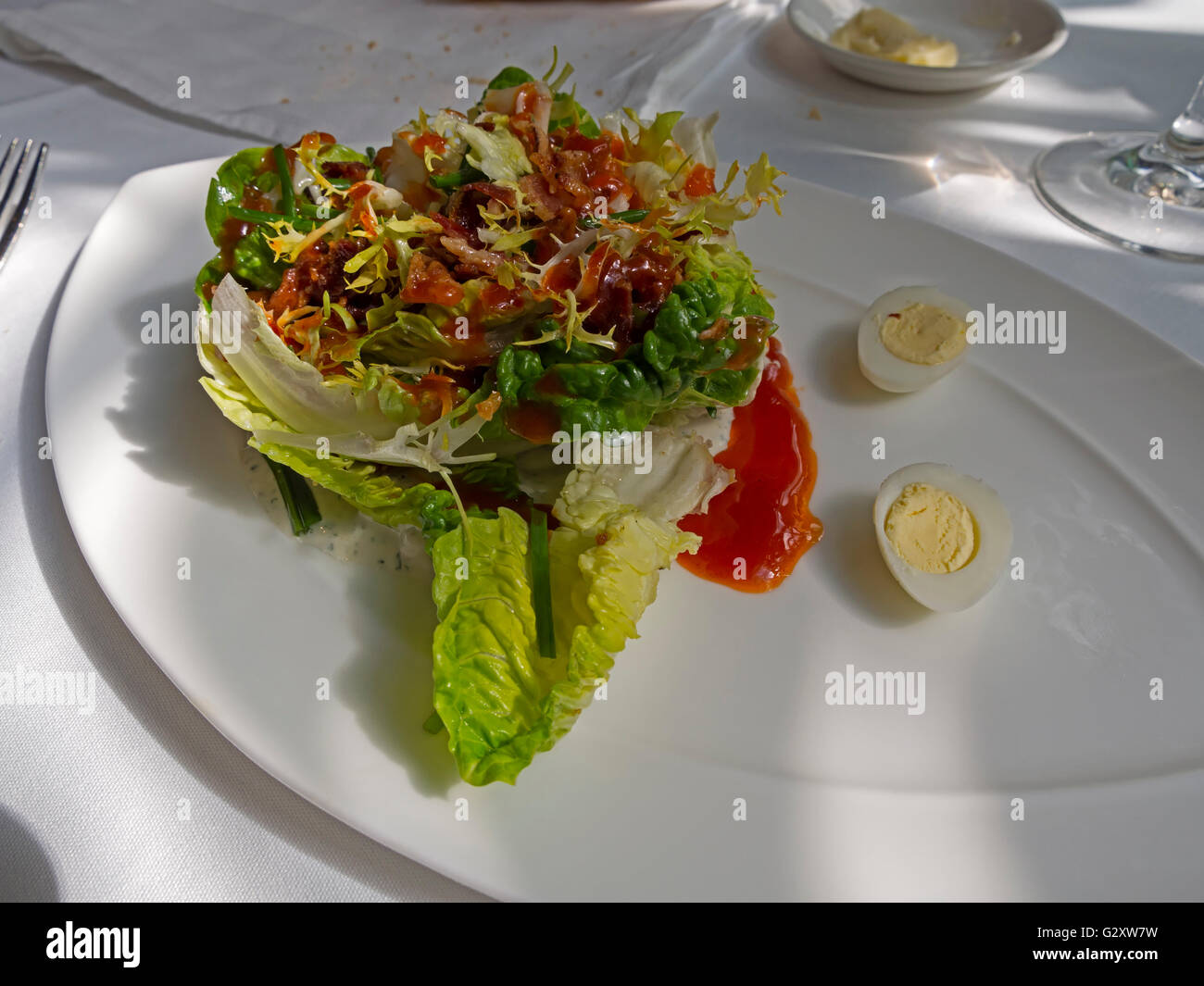 Grüner Salat mit Speck, Eiern Wachteln und einem würzigen dressing Stockfoto