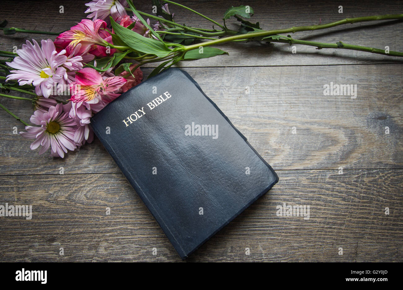 Bibel-Hintergrund. Bibel auf einem rustikalen Hintergrund mit einem frischen Blumenstrauß. Stockfoto