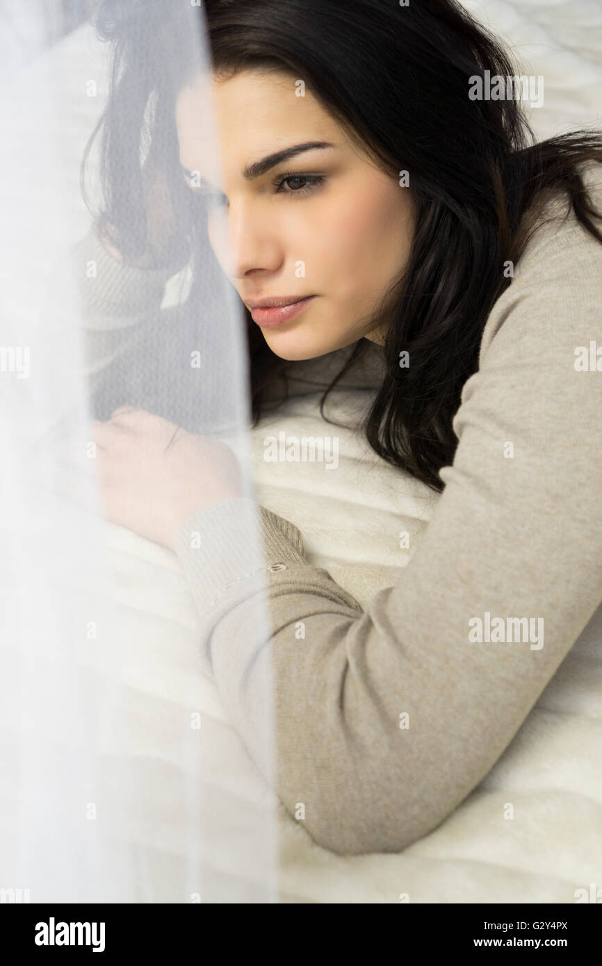 Nachdenkliche Frau im Bett Stockfoto