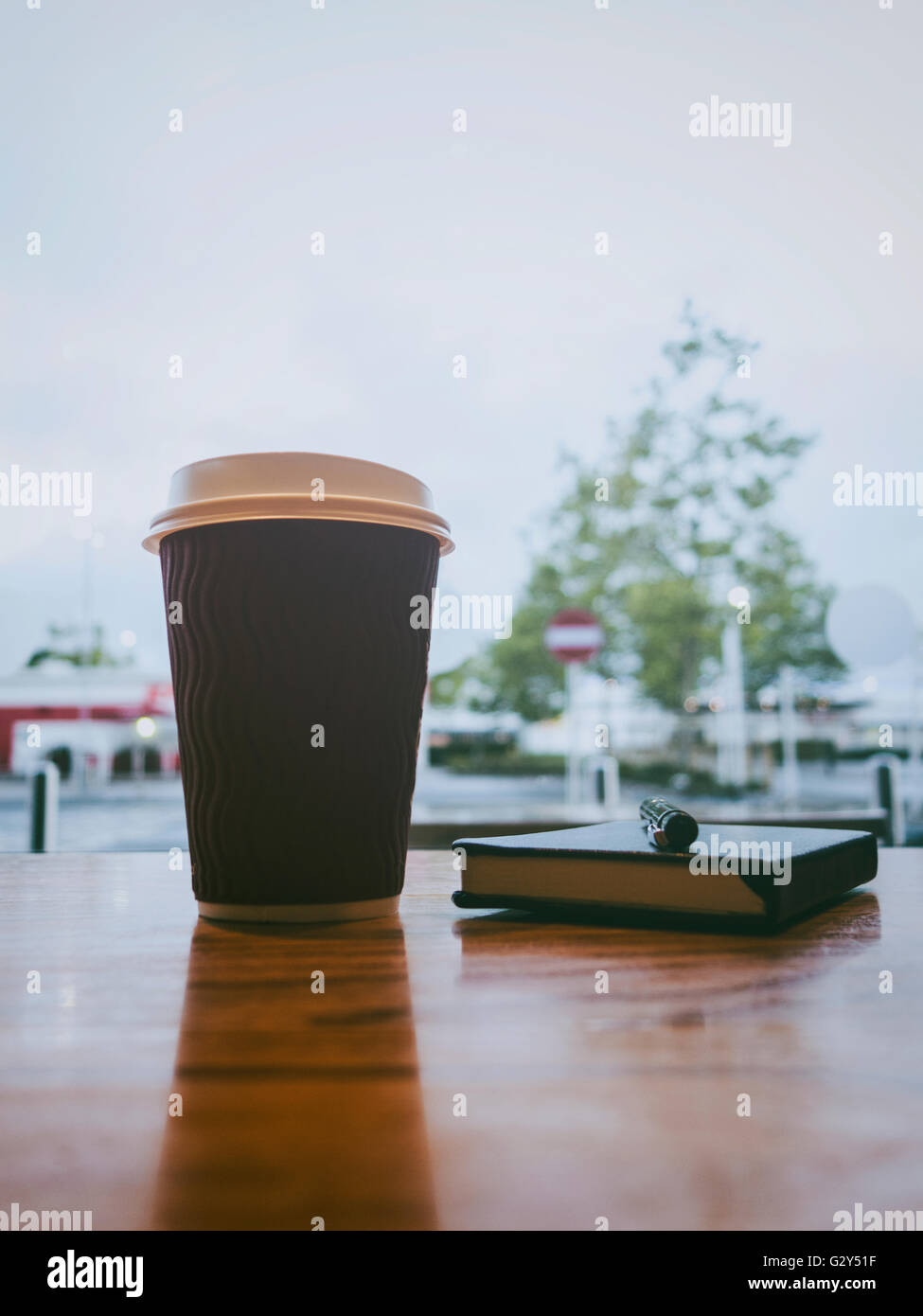 Tasse Kaffee mit einem Journal auf dem Tisch im freien Stockfoto