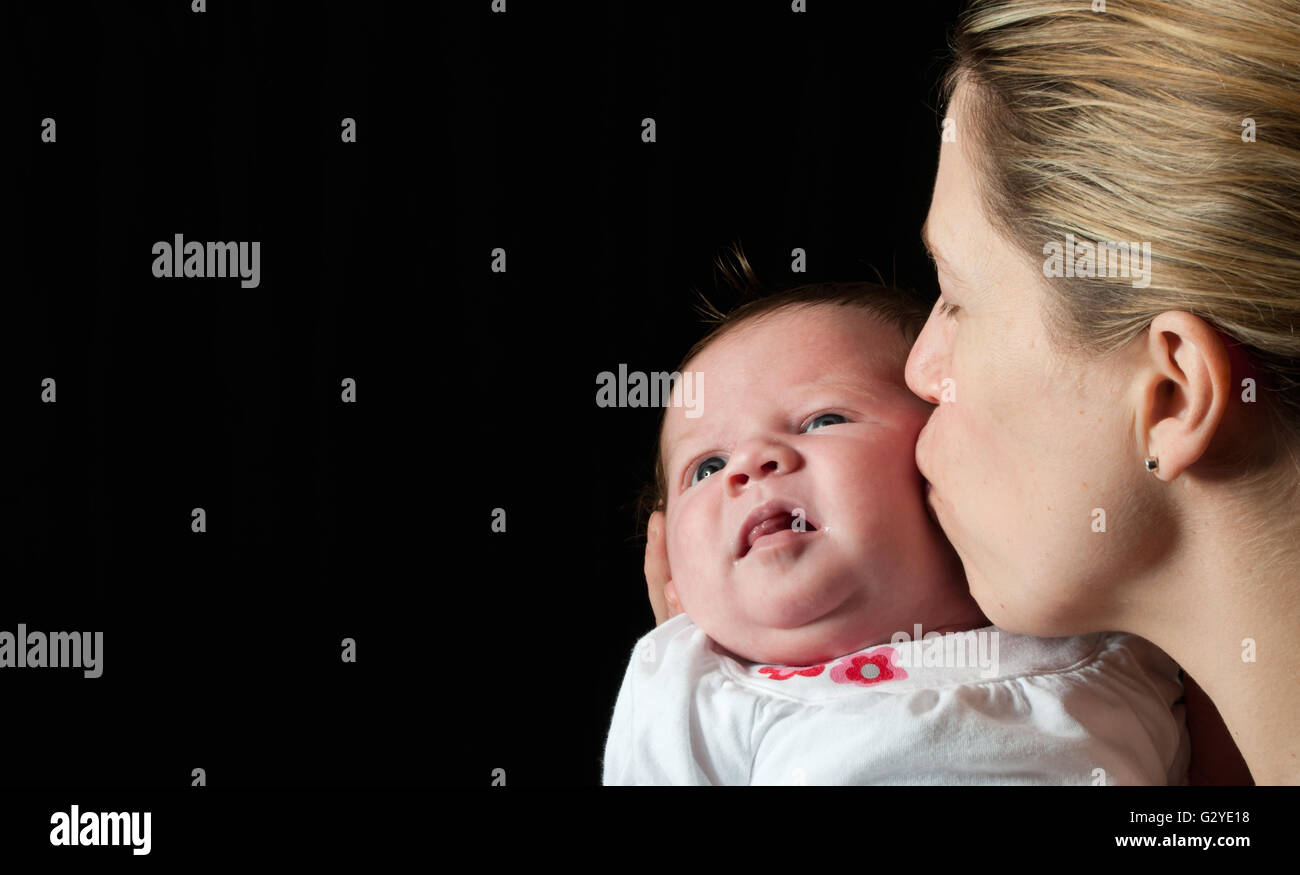 Mutter ihr Neugeborenes Babymädchen küssen Stockfoto