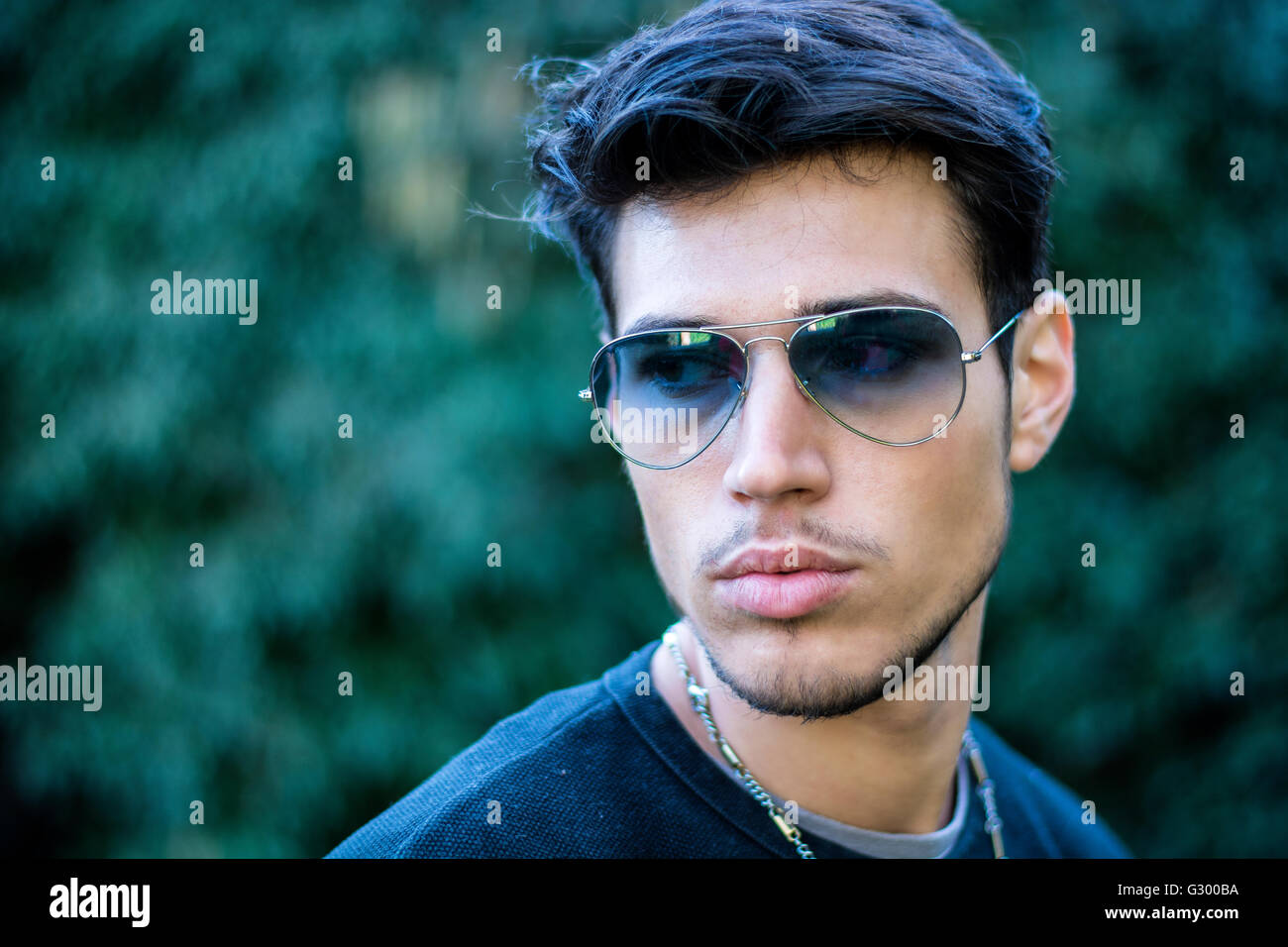 Kopfschuss hübscher junger Mann in Stadtstraße, Blick auf eine Seite mit Sonnenbrille Stockfoto
