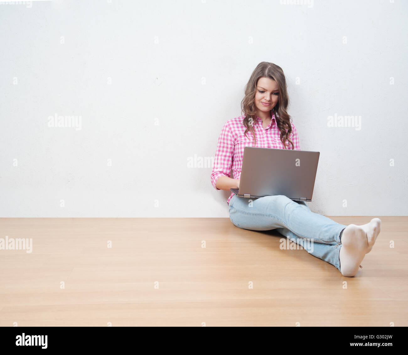 Junge kreative Frau sitzt in der Etage mit Laptop / Casual Blogger Frau Stockfoto