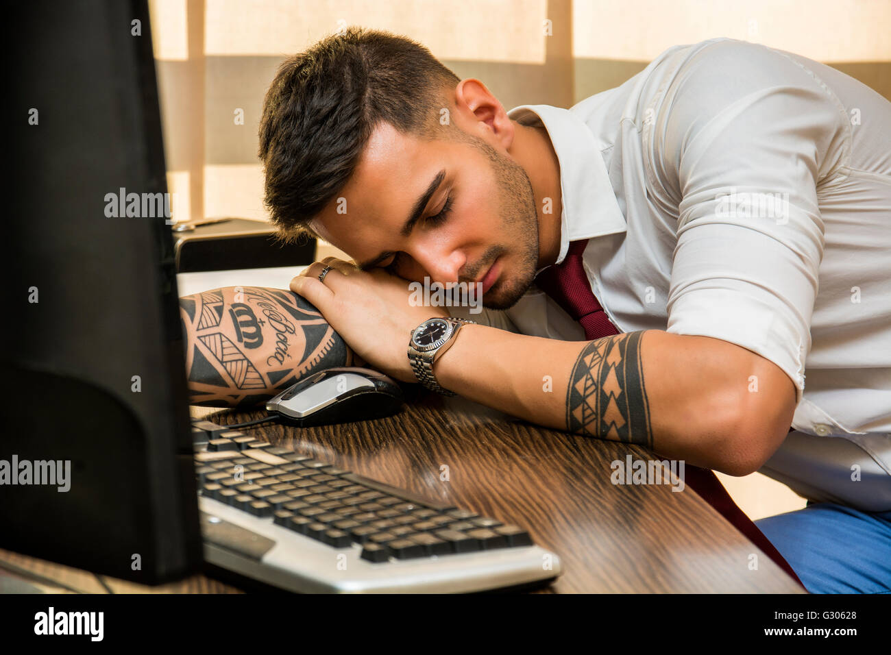 Überlastete, müde Jungunternehmer auf seinem Schreibtisch im Büro, vor Computer schlafen Stockfoto