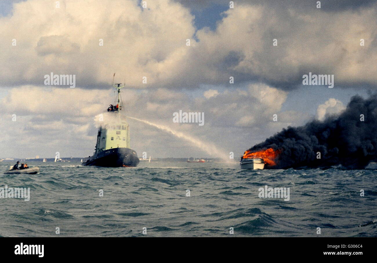 AJAXNETPHOTO - SOLENT, ENGLAND - Feuer auf See - versucht Hafen Schlepper Extniguish heftigen Feuer auf Motoryacht. FOTO: STEVE FOULKES/AJAX REF 6076 17 1 Stockfoto