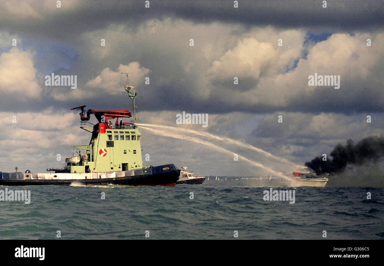 AJAXNETPHOTO - SOLENT, ENGLAND - Feuer auf See - versucht Hafen Schlepper Extniguish heftigen Feuer auf Motoryacht. FOTO: STEVE FOULKES/AJAX REF 6076 20 04 Stockfoto