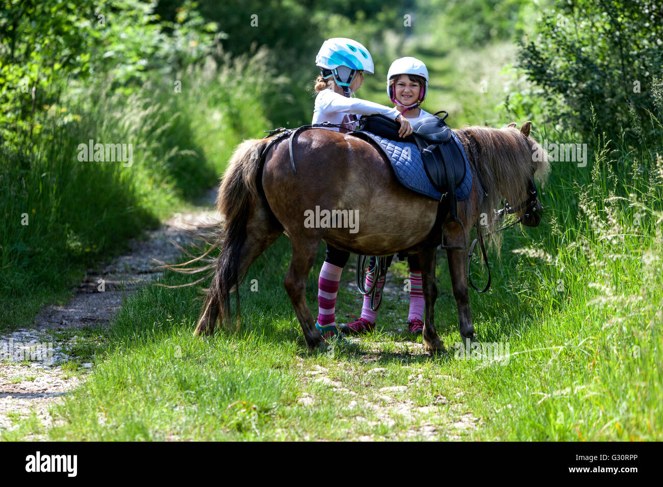 Zwei Mädchen 6-7 Jahre alt mit einem Pony auf der Straße in der Natur, Kind Pony Stockfoto