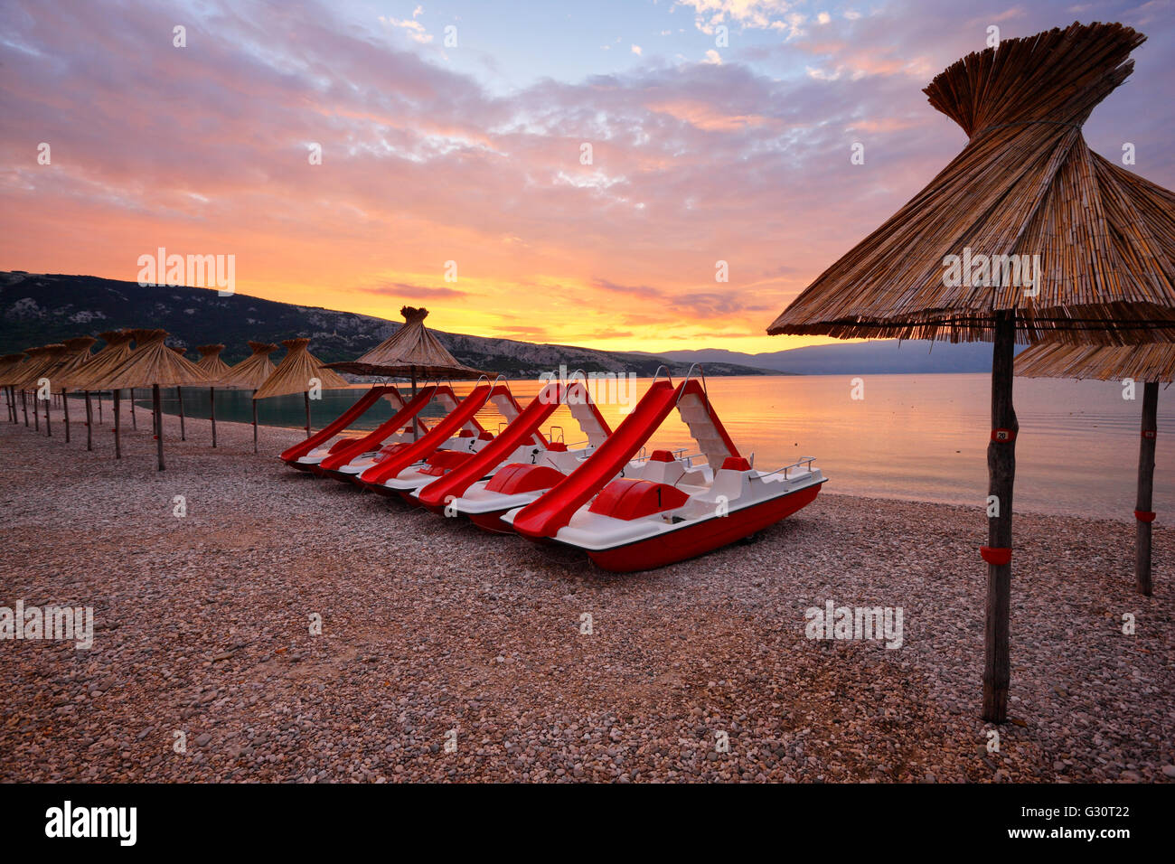 Stroh Sonnenschirme und Wasser Tretboote am Strand in Baska, Insel Krk Stockfoto