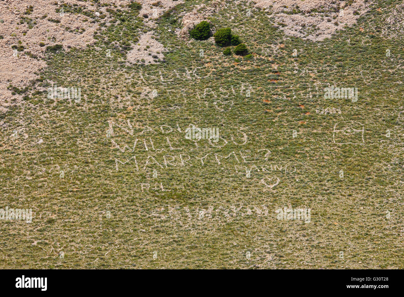 Schlägt mit riesigen Felsen Buchstaben auf Wiese Stockfoto