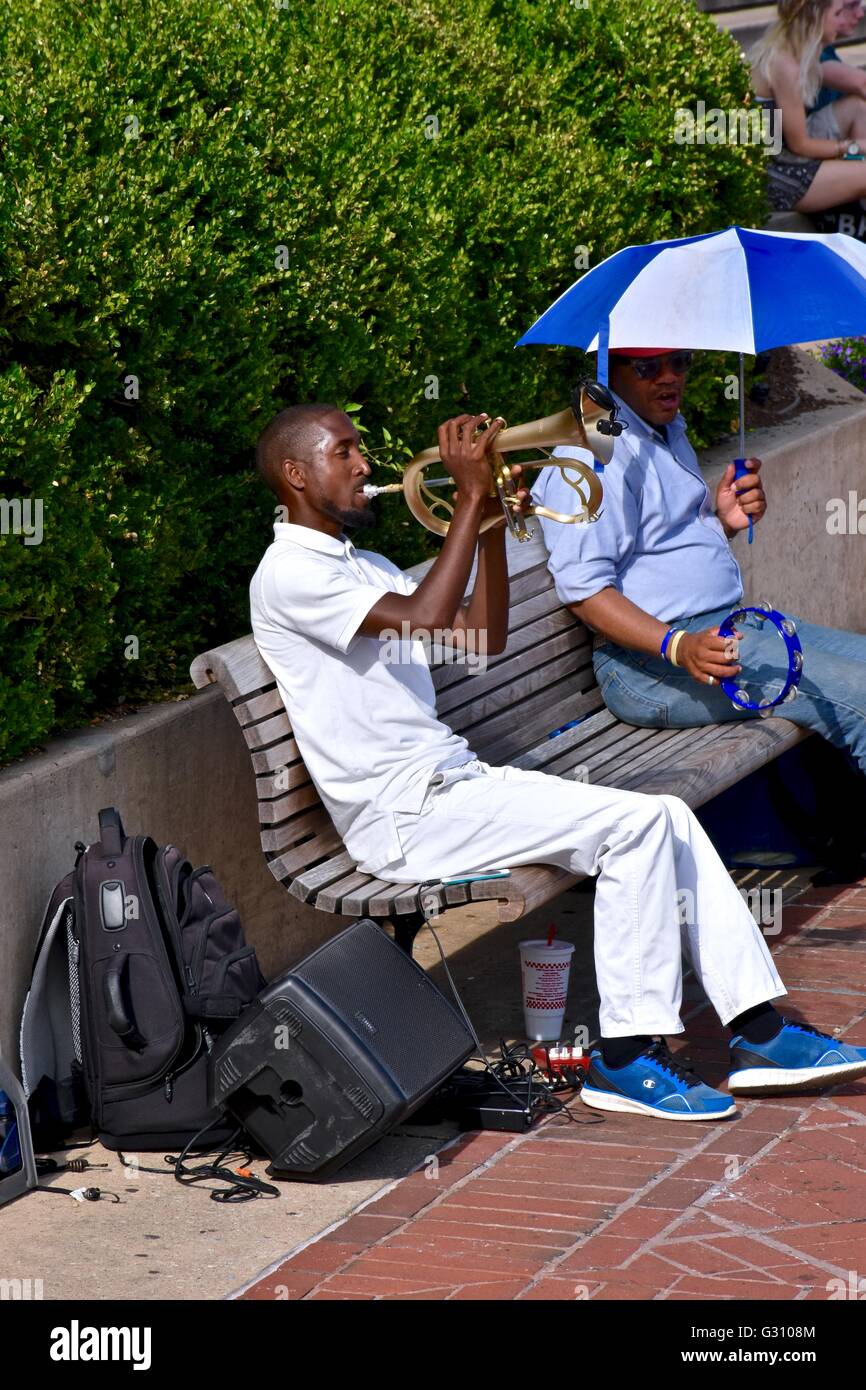 Ein afrikanischer amerikanischer Mann, ein Instrument zu spielen, während Sie auf einer Parkbank sitzen. Stockfoto