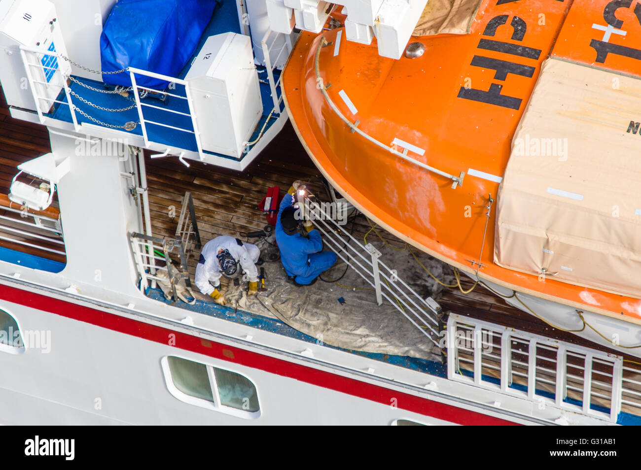 Crew-Mitglieder Schweißen einen Reparatur-Patch auf einem Kreuzfahrtschiff, während Touristen an Land sind.  Costa Maya, Mexiko Stockfoto