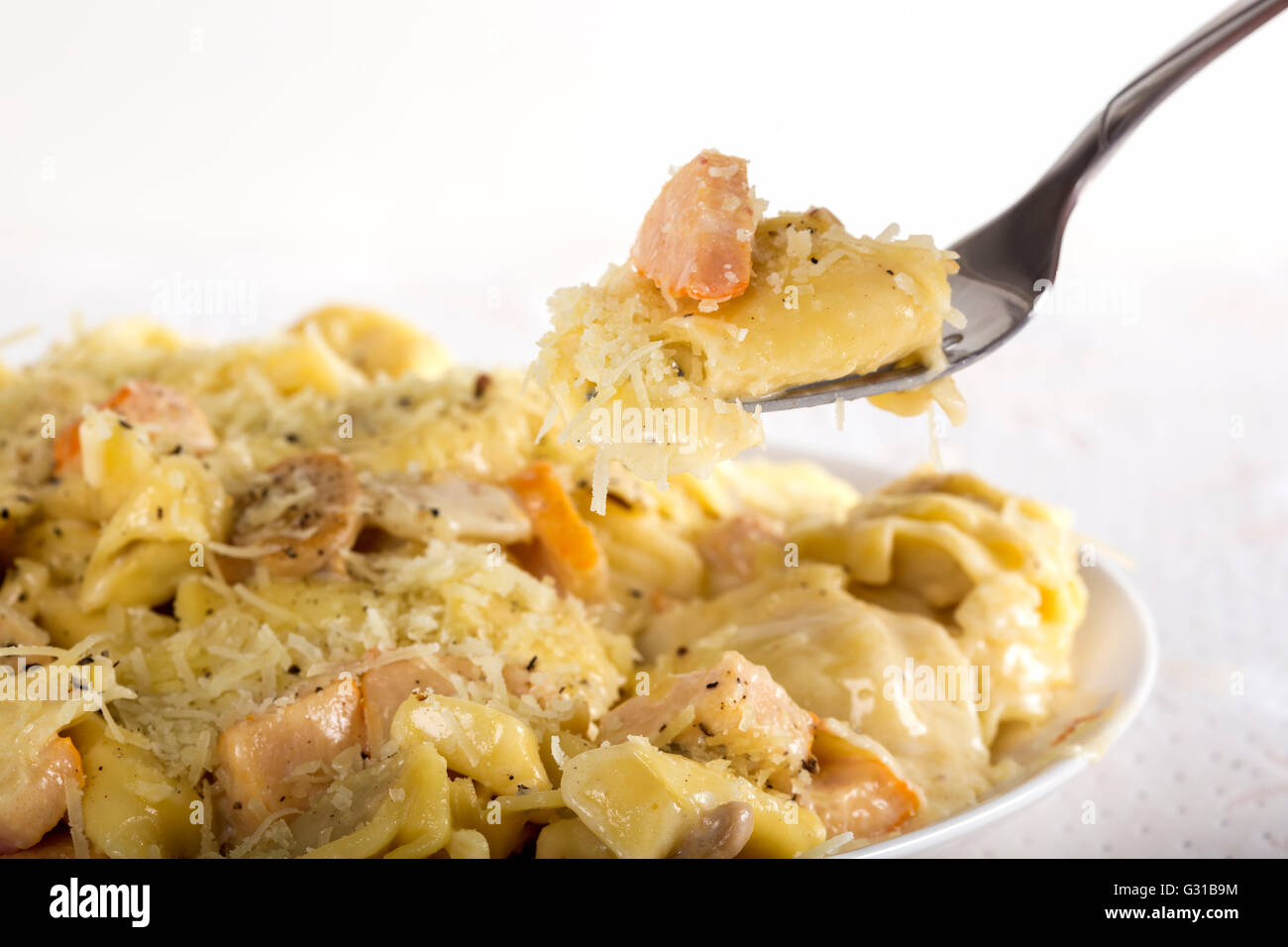 Tortellini und Ravioli mit saurer Sahne, Hühnerfleisch und Champignons auf Platte Stockfoto