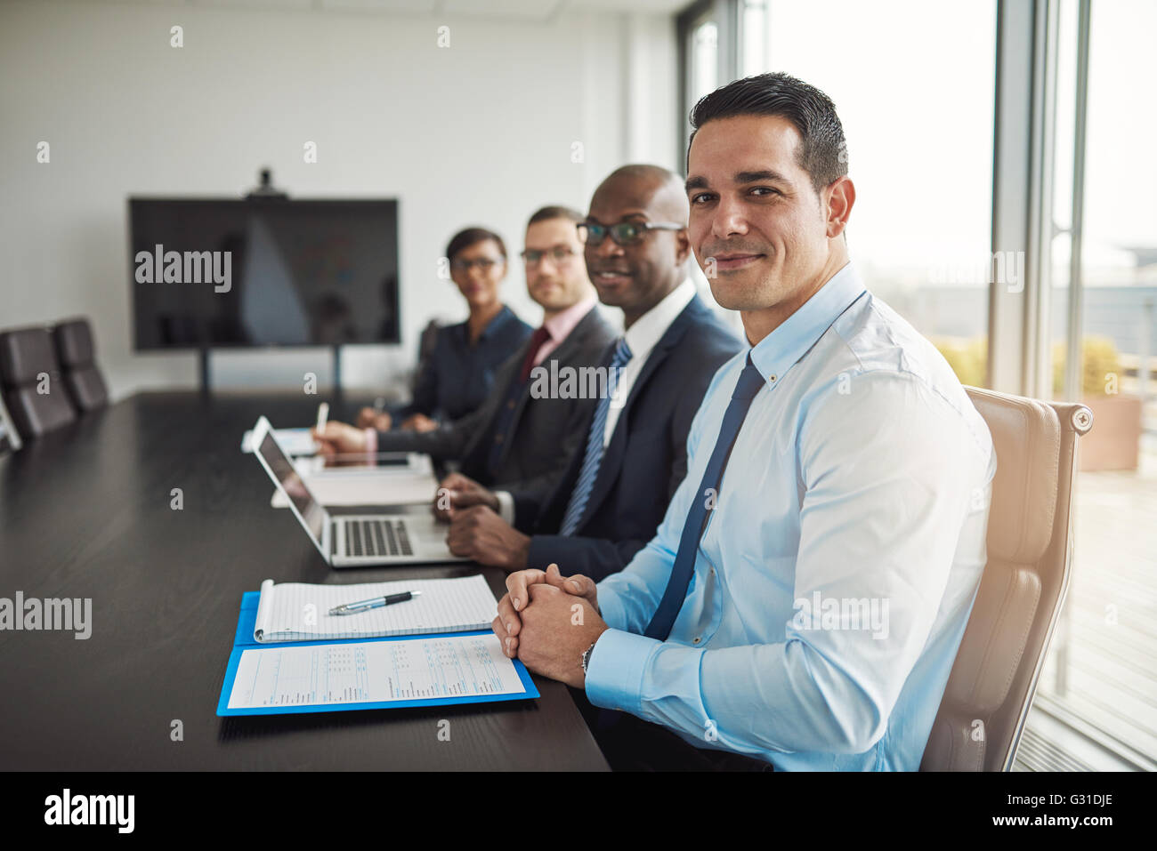 Gemischtrassig executive Business-Team in einem Meeting sitzen an einem Tisch Unternehmenskonferenz mit Fokus auf ein Hispanic Mann in den Vordergrund Stockfoto