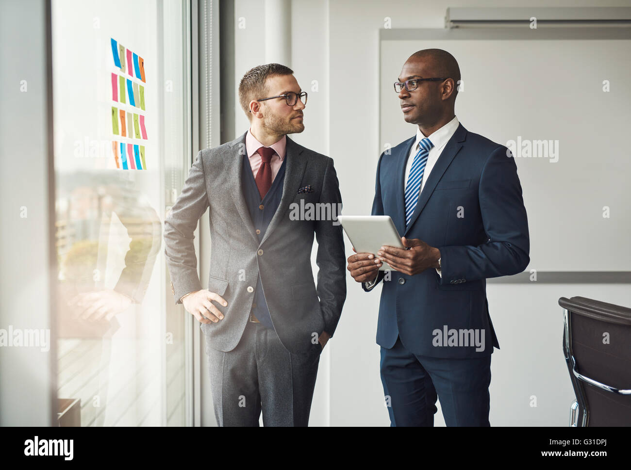Zwei intelligente Business-Manager oder Co Büroangestellte in einem Diskussion steht vor einem Fenster mit bunten Memos auf dem Glas Stockfoto