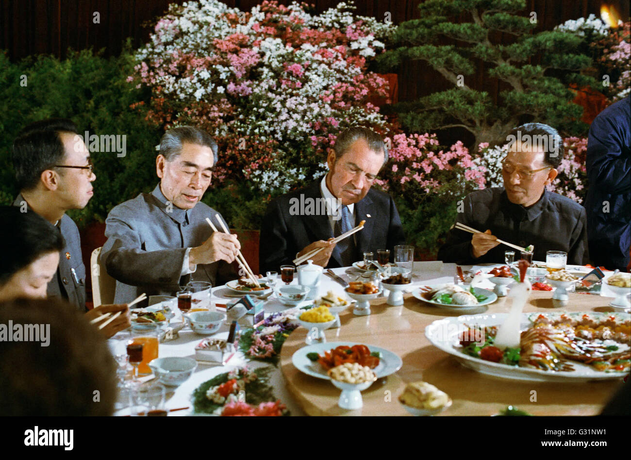 US-Präsident Richard Nixon versucht mit Stäbchen bei einem Bankett gegeben ihm zu Ehren von kommunistischen Führer Premier Zhou Enlai, links, und kommunistische Partei Führer Chang Chung-Chiao, rechts in die große Halle des Volkes 26. Februar 1972 in Peking, China. Stockfoto