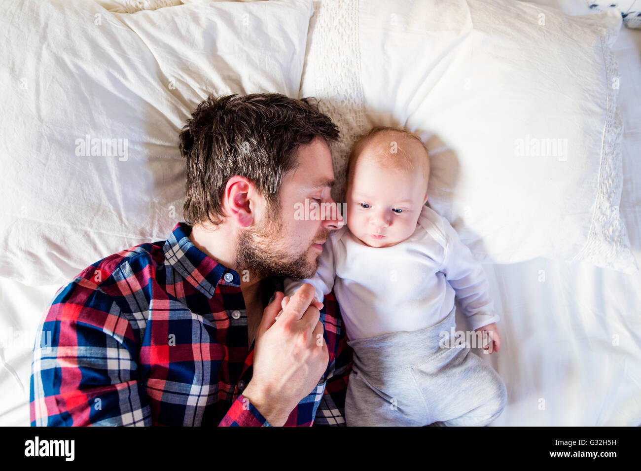 Baby Boy auf Bett, neben seinem Vater Stockfoto