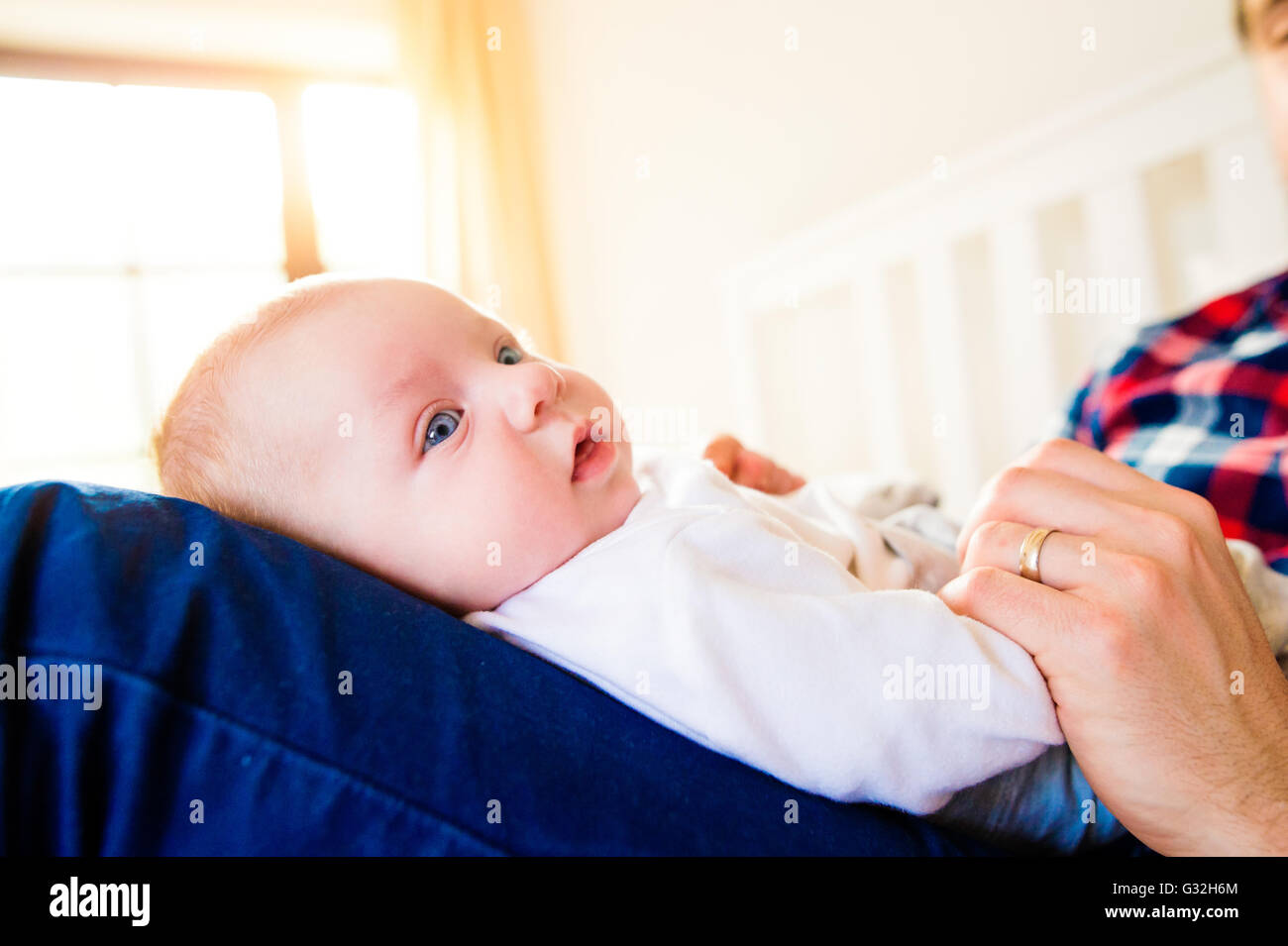 Baby Boy im Besitz seines Vaters sitzt auf Bett Stockfoto