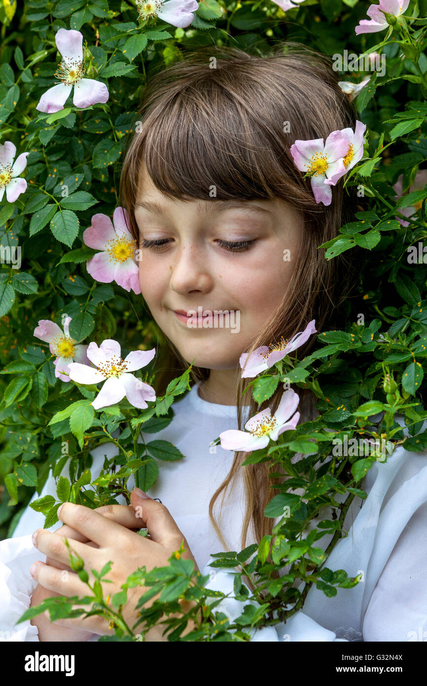 7-jähriges Mädchen Kind in wilden Rosen blühende Blumen Kindergesicht Stockfoto
