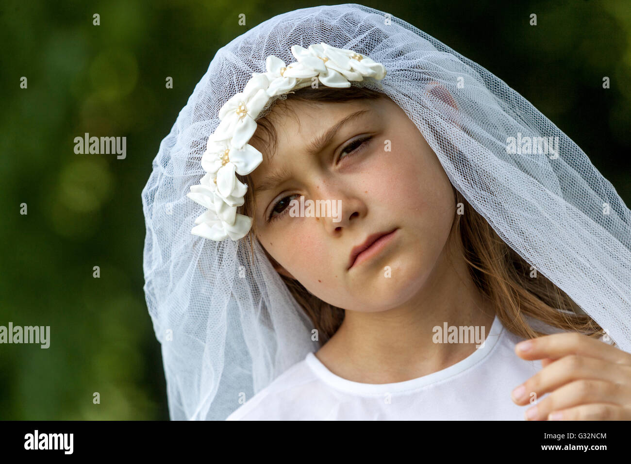 Alter der Unschuld 6-7 Jahre altes Mädchen Weißer Braut Schleier Braut Spiel Kindergesicht trauriger Ausdruck trauriges Mädchen draußen Stockfoto