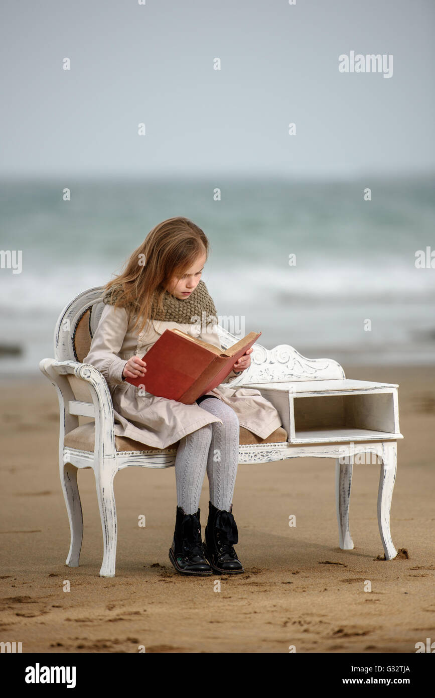 Mädchen sitzen im Stuhl am Strand ein Buch lesen Stockfoto