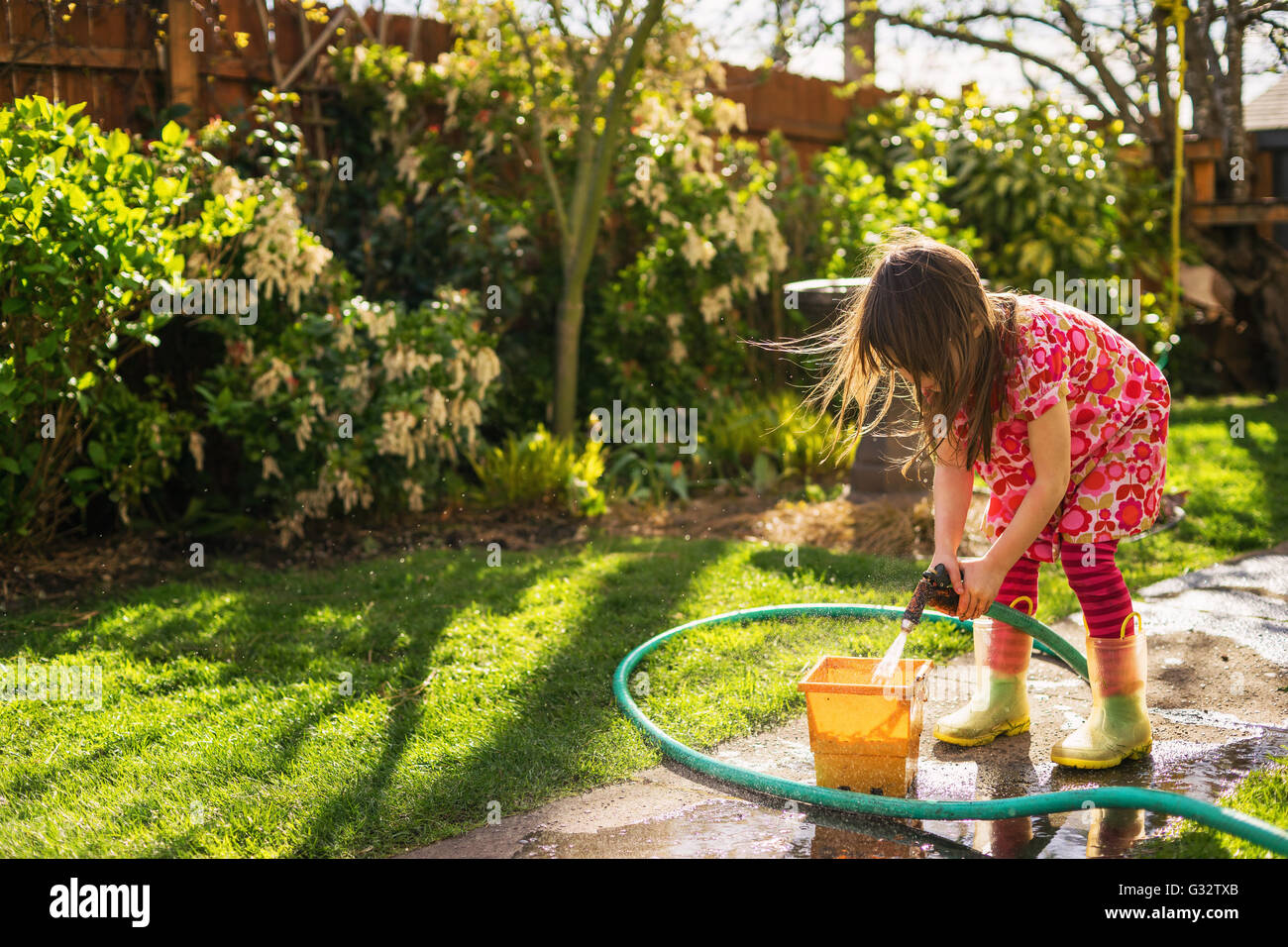 Mädchen stehen im Garten Füllung Eimer mit Wasser Stockfoto