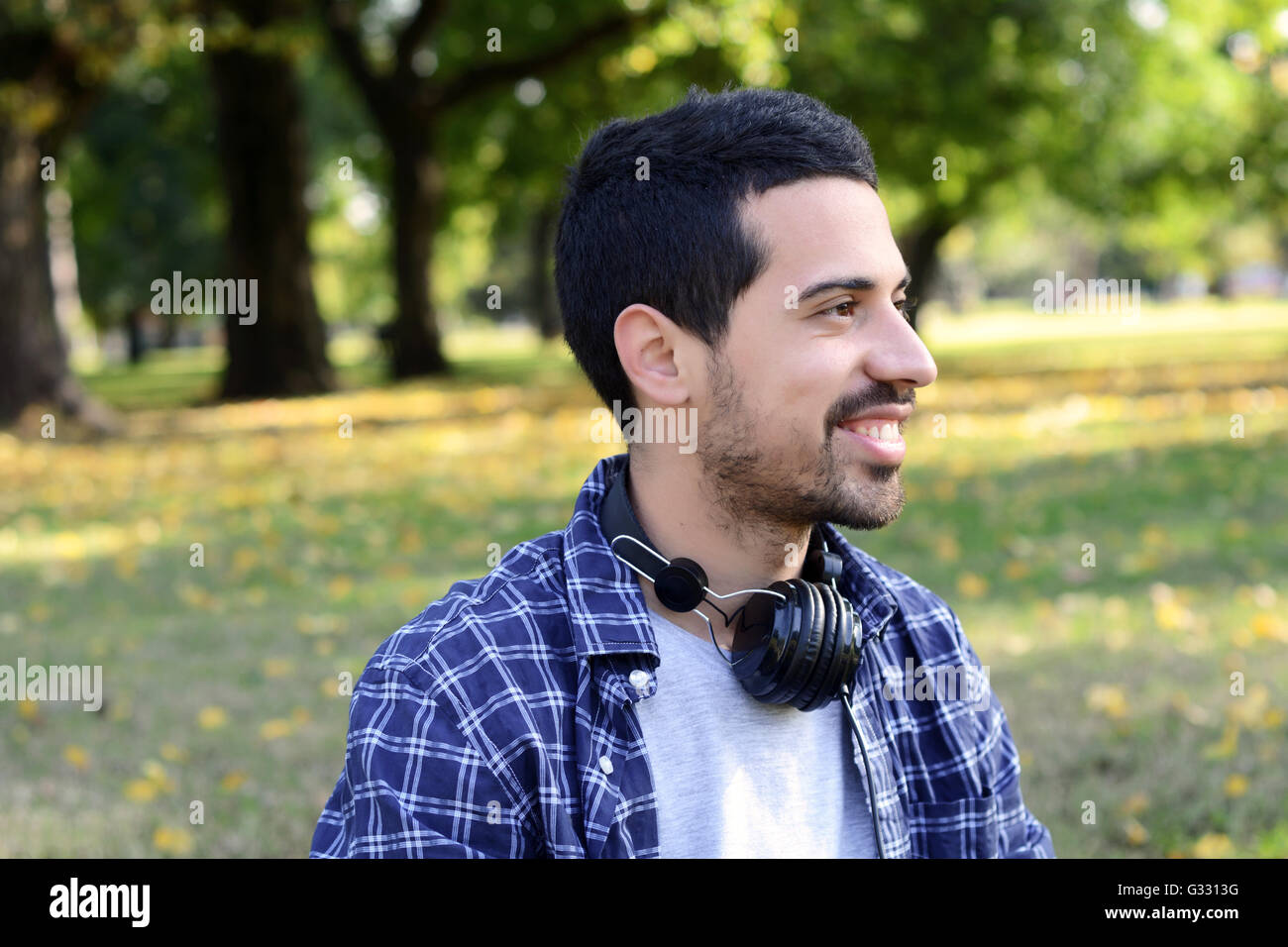 Nahaufnahme eines schönen jungen Mann mit Kopfhörern in einem Park. Im Freien. Stockfoto