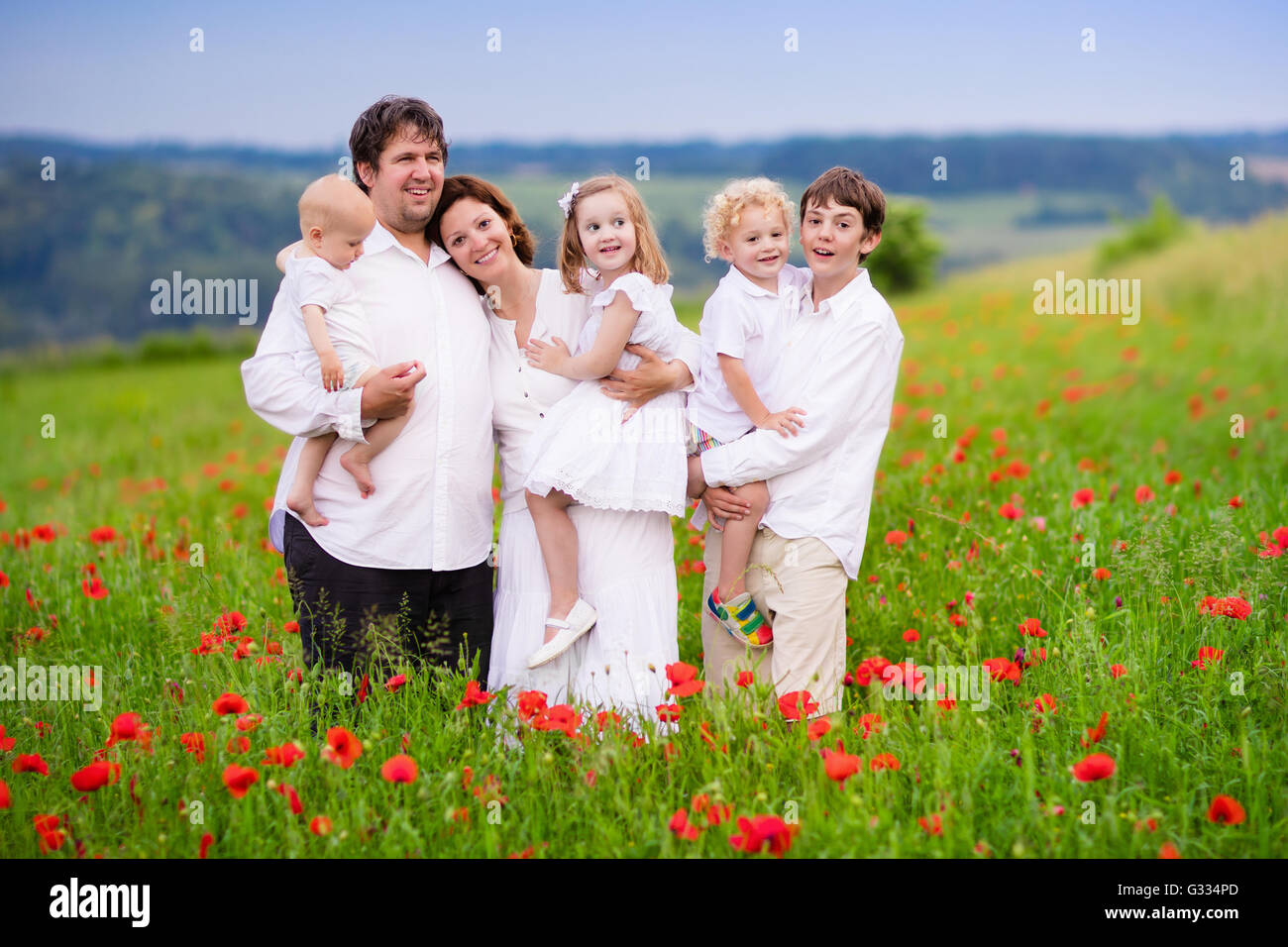 Große, glückliche Familie mit vier Kindern in roter Mohn Blumenfeld. Stockfoto