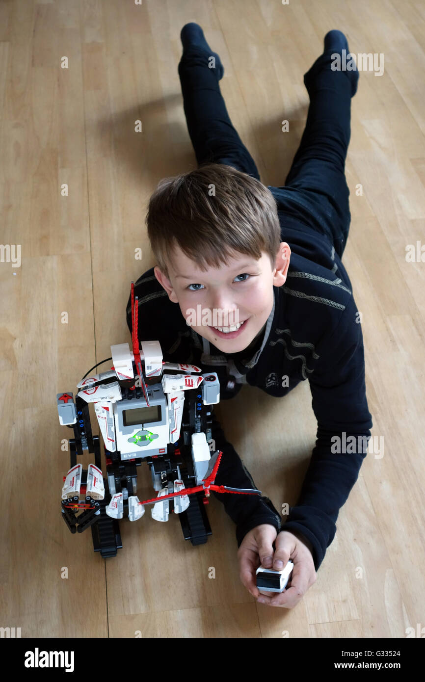 Berlin, Deutschland, freut sich jung neben seinem LEGO EV3-Roboter auf dem Boden Stockfoto
