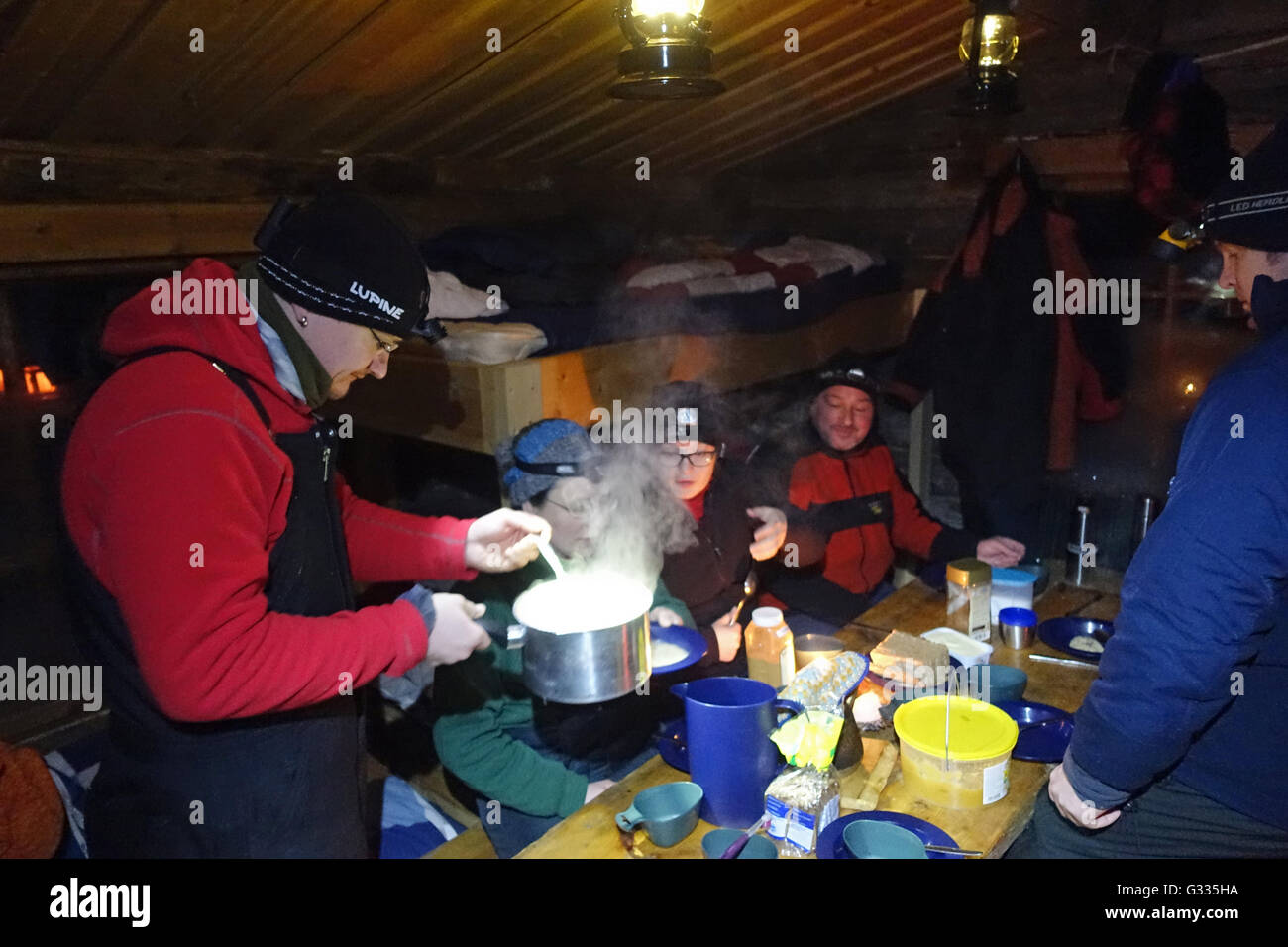 ? K skero, Finnland, Menschen essen ihr Abendessen in einem kalten Holzhütte Stockfoto