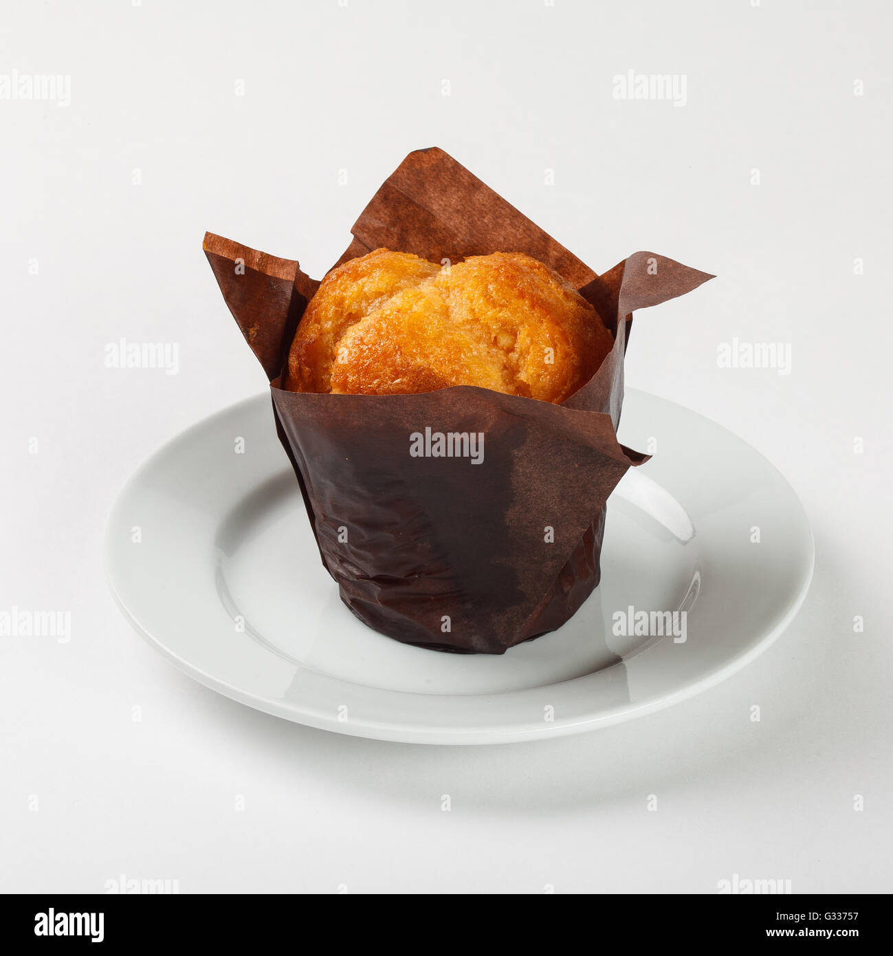 Leckere Muffin Kuchen in braunem Papier auf die Platte auf weißem Hintergrund. Schließen Sie die Seitenansicht. Stockfoto