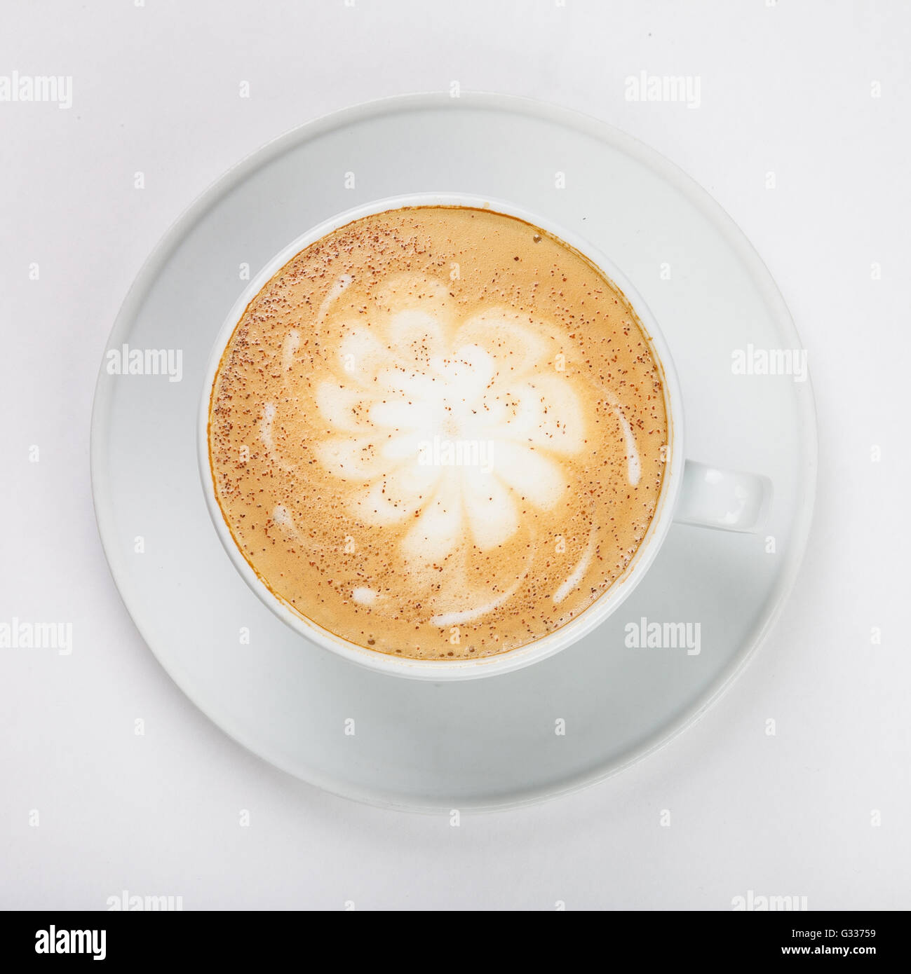 Leckeren Cappuccino in einer weißen Tasse auf dem Teller auf weißem Hintergrund. Ansicht von oben hautnah. Stockfoto